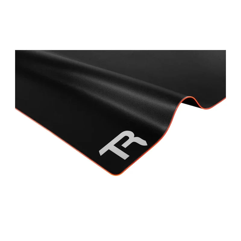 Trak Racer premium RGB floor mat, close-up of lifted corner showing TR logo and orange trim